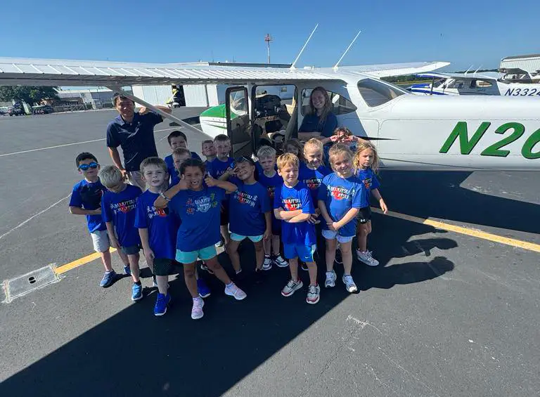 Summer camp kids on field trip to airport next to airplane in Waco Texas